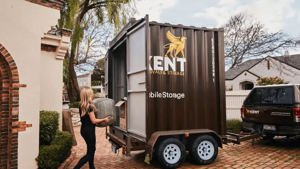 A young woman carries her striped ottoman into a Kent Storage portable mobile unit for flexible secure storage with Kent Removals & Storage.